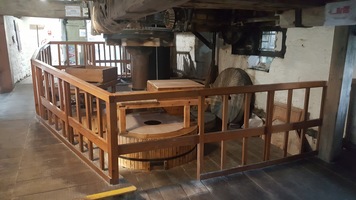 First room in the top floor of the Mill showing quern stones for grinding the grain, a central axel and hopper for putting the wheat in.