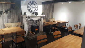 Millers Tea Room - wooden tables and chairs, a log fire and a large Roman numeral clock on the wall.