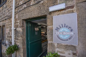 Entrance to Millers Tea Room through an open green door with a sign saying Miller's Tea Room to the right