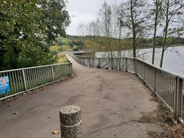Entrance to the bridge over the dam at the end of the reservoir. A concrete bridge with metal railings.