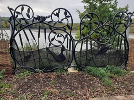 A wrought iron piece of public art depicting leaves, birds and fish. The reservoir is visible behind it.